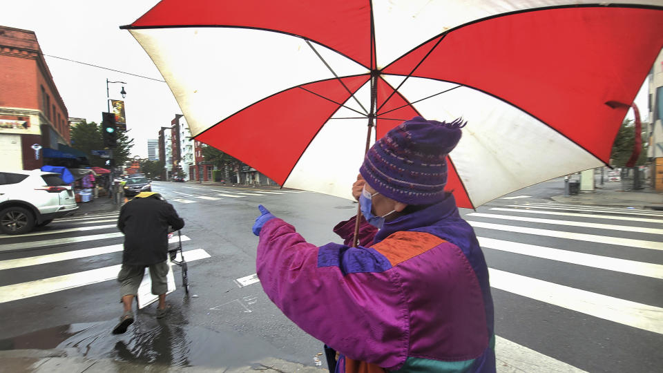 People walk through the rain in the Chinatown district of Los Angeles, Monday, Nov. 7, 2022. A new Pacific storm is bringing snow, rain and wind to California. (AP Photo/Damian Dovarganes)