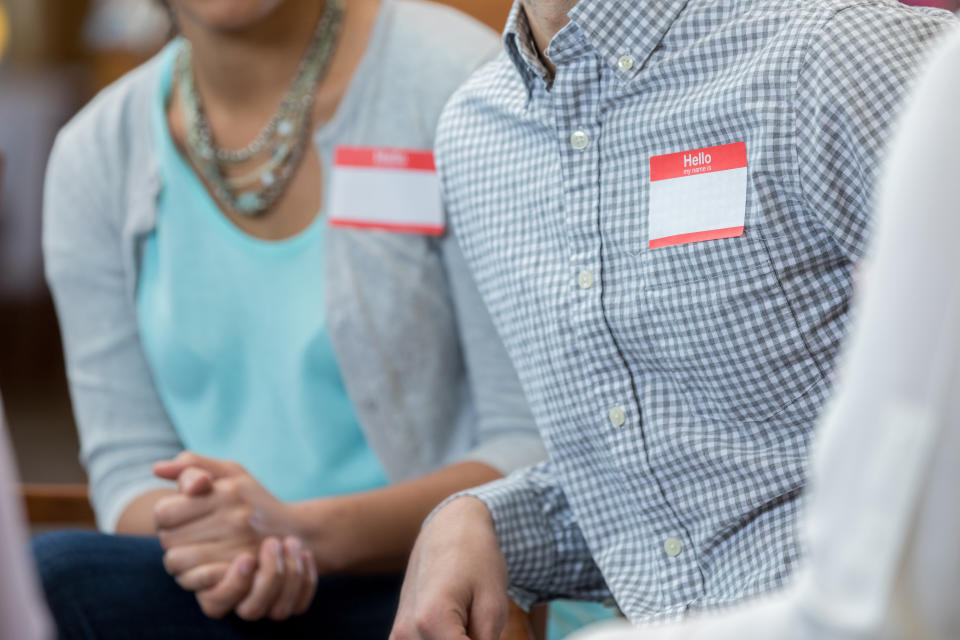 Unrecognizable man and woman wear name tags during meeting. Focus is on the name tags.