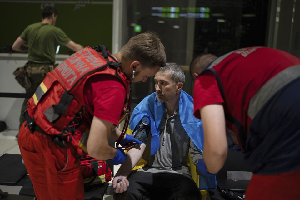 Dos médicos comprueban el estado de salud de Ivan Levytskyi tras el final de su cautiverio ruso, en el aeropuerto de Kiev, Ucrania, el 29 de junio de 2024. Diez ucranianos que llevaban años retenidos fueron liberados de su cautiverio ruso con la mediación del Vaticano, según el presidente de Ucrania, Volodymyr Zelenskyy. (AP Foto/Alex Babenko)