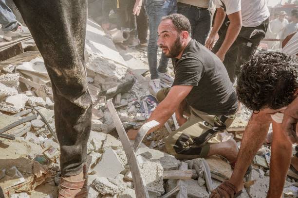 People gather around a building demolished by Israeli airstrikes to rescue injured civilians and retrieve bodies from the rubble (Middle East Images/AFP via Getty)