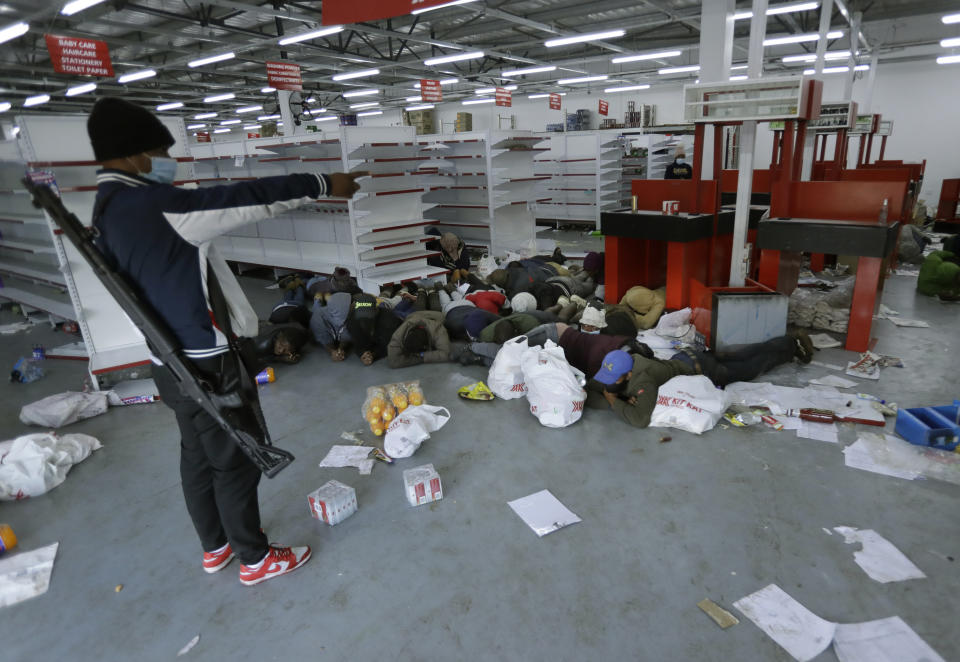 A security person aprehends looters inside a store in Vosloorus near Johannesburg, Tuesday July 13, 2021. South Africa's rioting continued Tuesday with the death toll rising to 32 as police and the military struggle to quell the violence in Gauteng and KwaZulu-Natal provinces. The violence started in various parts of KwaZulu-Natal last week when Zuma began serving a 15-month sentence for contempt of court. (AP Photo/Themba Hadebe)