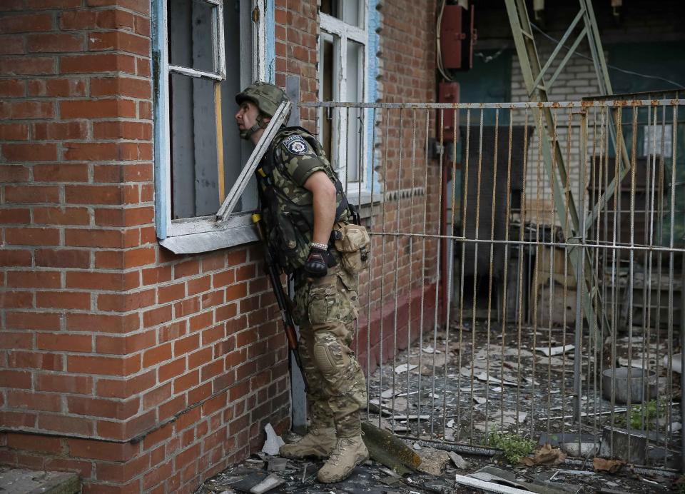 A member of Ukrainian police special task force "Kiev-1" looks through a window during a patrol in the eastern Ukrainian village of Semenovka, near Sloviansk, July 14, 2014. Ukraine on Monday accused Russian army officers of fighting alongside separatists in the east of the country and said Moscow was once more building up its troops on the joint border. REUTERS/Gleb Garanich (UKRAINE - Tags: POLITICS CIVIL UNREST MILITARY CONFLICT)