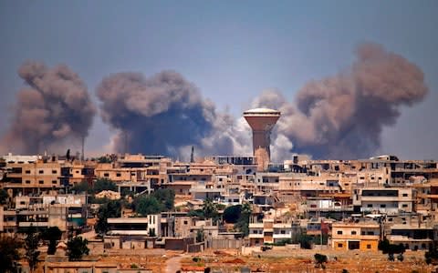 Smoke rises above rebel-held areas of the city of Deraa during reported airstrikes by Syrian regime forces - Credit: AFP