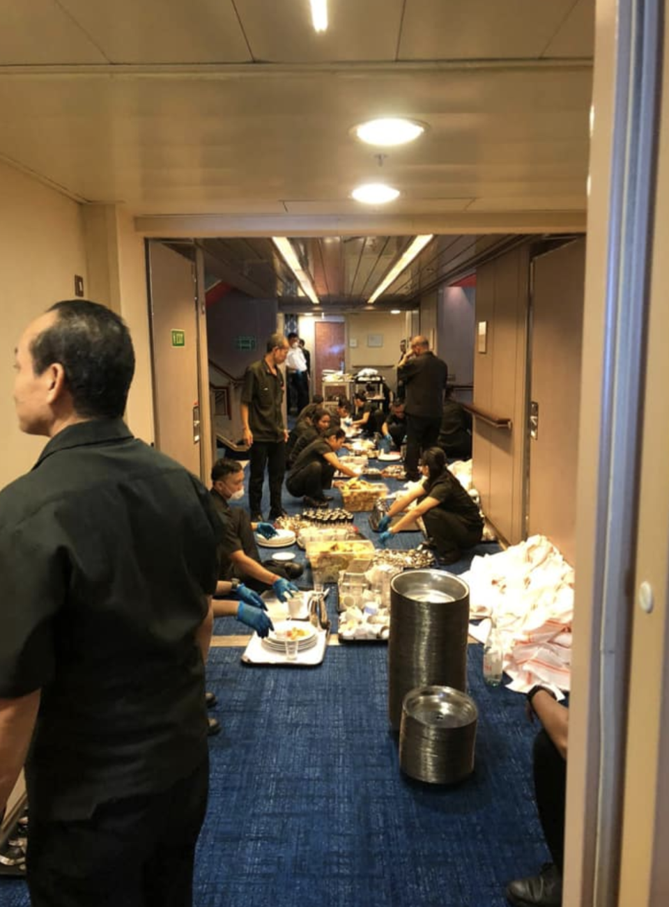 Cruise crew members are seen stacking dirty dishes in the cruise's hall. Source: Facebook