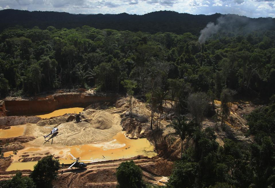 FILE - Helicopters are visible at an illegal mining camp during an operation by Brazil's environmental agency aimed at combating illegal mining in Yanomami Indigenous territory, Roraima state, Brazil, Feb. 11, 2023. Yanomami leaders have urged people not to buy gold jewelry at all, regardless of its source, because demand for the precious metal drives gold prices up and draws miners into their territory. (AP Photo/Edmar Barros, File)