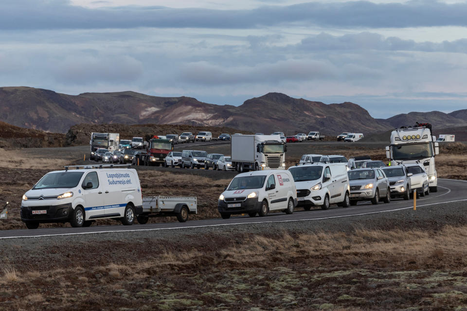 A line of cars is parked along a winding highway as residents wait to reach their homes in the fishing town of Grindavik.