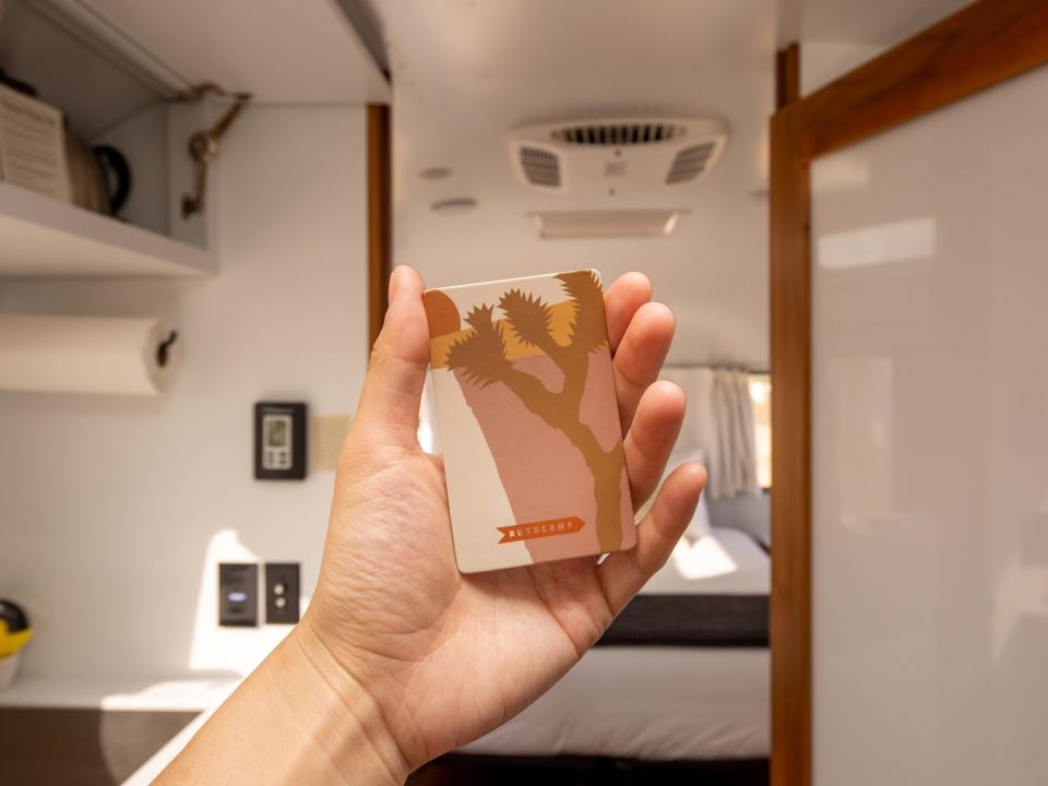 A hand holding up an Autocamp key card.