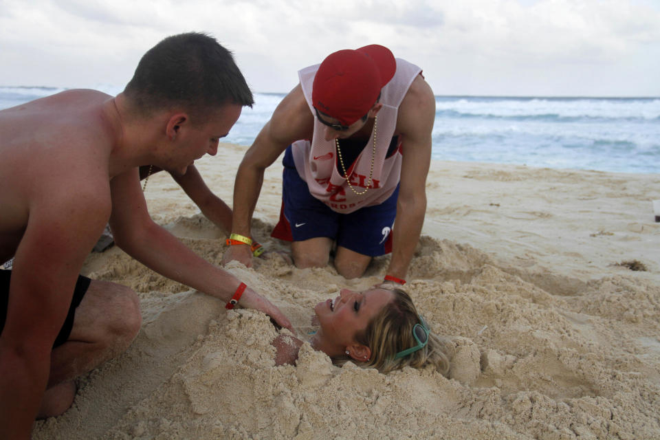 In this March 7, 2012 photo, people bury eachother in the sand on the beach during Spring Break in Cancun, Mexico. While American tourism to Mexico slipped a few percentage points last year, the country remains by far the biggest tourist destination for Americans, according to annual survey of bookings by the largest travel agencies. (AP Photo/Israel Leal)