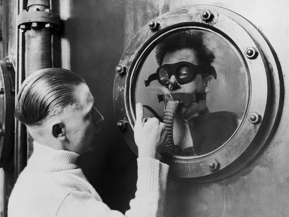 An instructor signals through a porthole to a seaman at the bottom of a 15 foot tank, during submarine crew training in 1939.