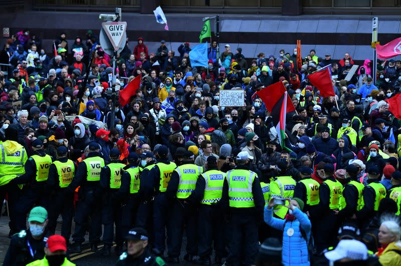 Agentes de policía montan guardia mientras la gente participa en una protesta durante la Conferencia de las Naciones Unidas sobre el Cambio Climático (COP26), en Glasgow, Escocia, Gran Bretaña, el 6 de noviembre de 2021.