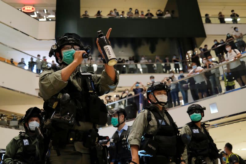 A riot police wearing face mask to avoid the spread of the coronavirus disease (COVID-19) holds a pepper spray as he tries to disperse anti-government protesters as they stage a rally at a shopping mall, in Hong Kong