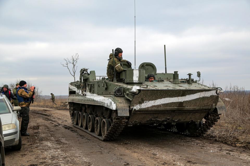 A cameraman films as an armored vehicle rolls outside Mykolaivka, Donetsk region, the territory controlled by pro-Russian militants, eastern Ukraine, Sunday, Feb. 27, 2022.