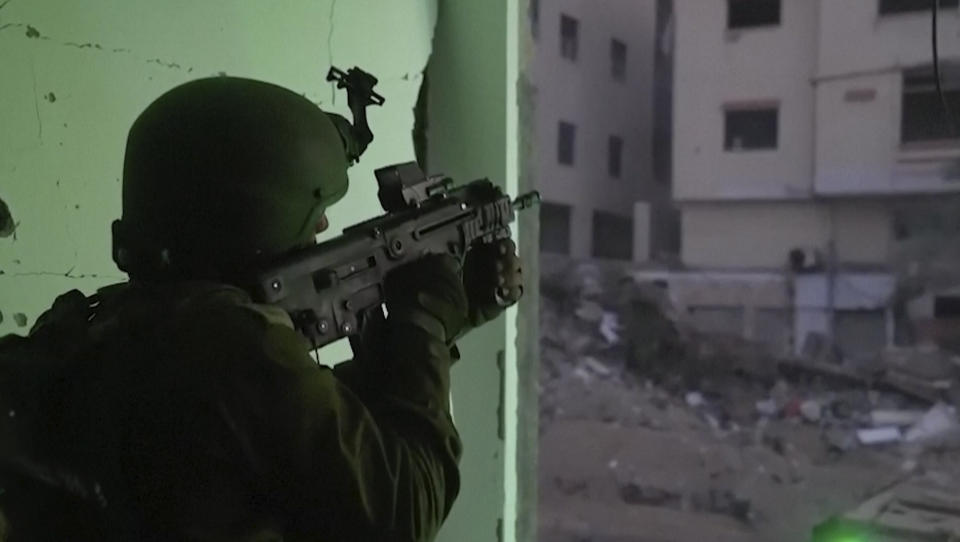 In this image taken from a video released by the Israeli Defense Forces on Nov. 14, 2023, an Israeli soldier holds a weapon in Gaza City. As the military sets its sights on southern Gaza in its campaign to stamp out Hamas, key challenges loom. International patience for a protracted invasion has begun to wear thin. And with some 2 million displaced Gaza residents staying in crowded shelters in the south in dire conditions, a broad military offensive there could unleash a new humanitarian disaster during the cold, wet winter. (Israel Defense Forces via AP)