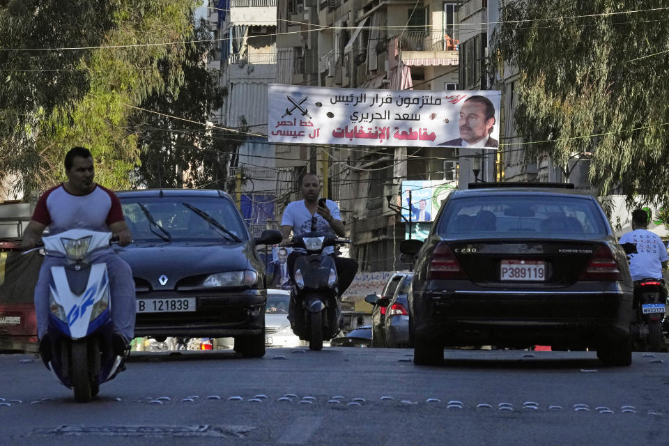 Vehicles drive past a banner showing a banner of former Lebanese Prime Minister Saad Hariri with Arabic text that reads "We are committed to President Saad Hariri's decision to boycott the elections," in Beirut, Lebanon, Tuesday, May 10, 2022. Given Lebanon's devastating economic meltdown, Sunday's parliament election is seen as an opportunity to punish the current crop of politicians that have driven the country to the ground. (AP Photo/Bilal Hussein)