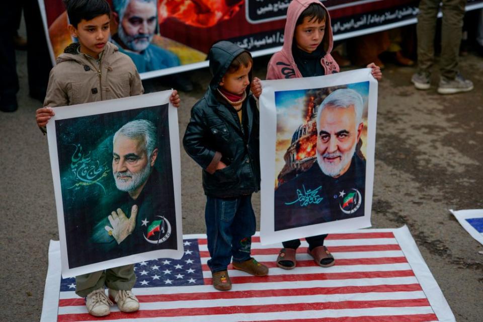 Shiite Muslim children stand on the US flag as they hold pictures of Iranian commander Qasem Soleimani during a protest Sunday. Source: Getty