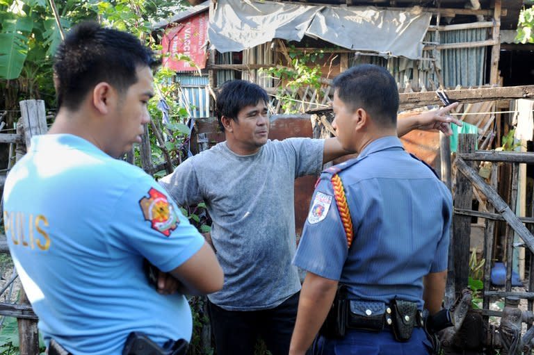 Philippine police talk to a relative of a victim following a deadly gun rampage in Kawit, about 40 kms (25 miles) south of Manila, on January 4, 2013. The gunman armed with a semi-automatic pistol killed at least seven people and wounded 12 others, before being shot and killed by police