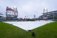 The tarp covers the field as the start of the game is delayed prior to the baseball game between the Cincinnati Reds and the Philadelphia Phillies, Wednesday, April 3, 2024, in Philadelphia. (AP Photo/Chris Szagola)