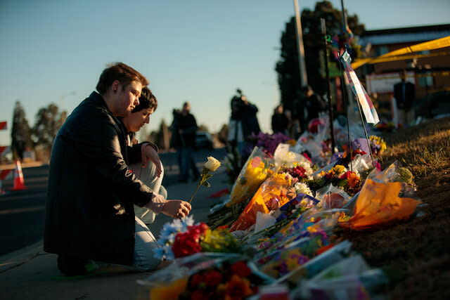 People leave flowers at the growing memorial at the scene