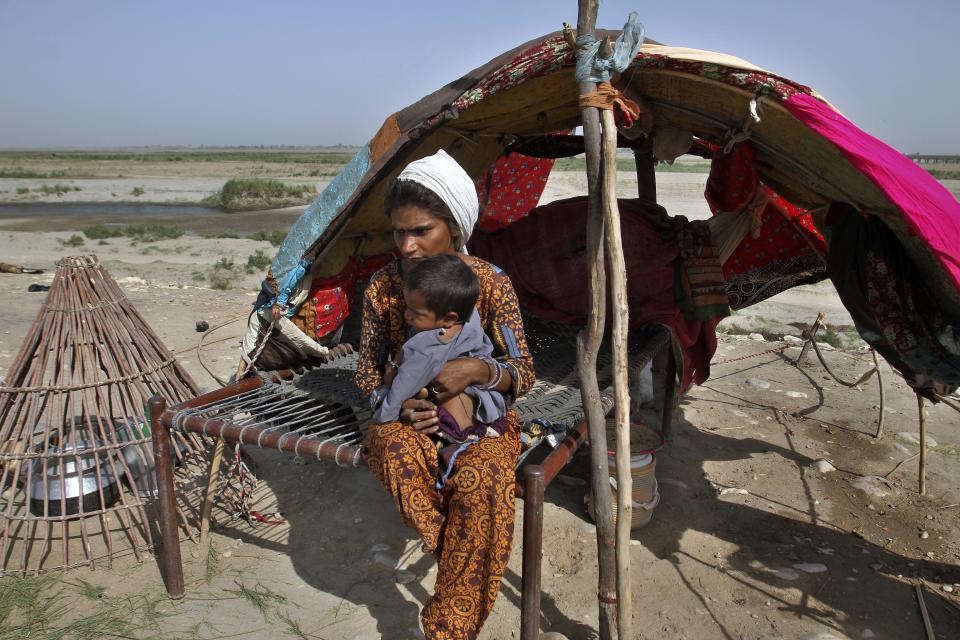 A nomad takes care of her child as they sit in at a hut, in Rajanpur, a district of Pakistan's Punjab province, Sunday, May 21, 2023. A year on from the floods in Pakistan that killed at least 1,700 people, destroyed millions of homes, wiped out swathes of farmland, and caused billions of dollars in economic losses, the country still hasn't fully recovered. (AP Photo/Asim Tanveer)