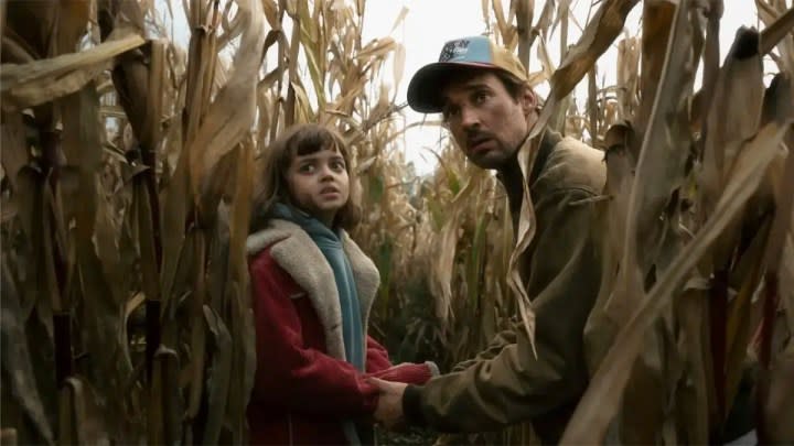 A father holds his daughter's hands in crop field in The Signal.