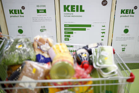 A woman pushes her cart which is full of groceries past a board bearing protein contents per 100 grams in Seoul, South Korea, August 8, 2016. Picture taken August 8, 2016. REUTERS/Kim Hong-Ji