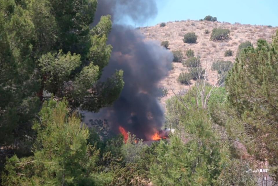 Fire and smoke rise from a home in Acton, California, near the site of a shooting at a local fire station on Tuesday.