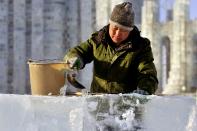 A worker pours water onto ice cubes to make them adhere to each other as he builds an ice sculpture ahead of the 30th Harbin Ice and Snow Festival, in Harbin, Heilongjiang province December 27, 2013. According to the festival organizers, nearly 10,000 workers were employed to build the ice and snow sculptures, which require about 180,000 square metres of ice and 150,000 square metres of snow. The festival kicks off on January 5, 2014. REUTERS/Sheng Li (CHINA - Tags: ENVIRONMENT SOCIETY BUSINESS EMPLOYMENT TRAVEL) CHINA OUT. NO COMMERCIAL OR EDITORIAL SALES IN CHINA