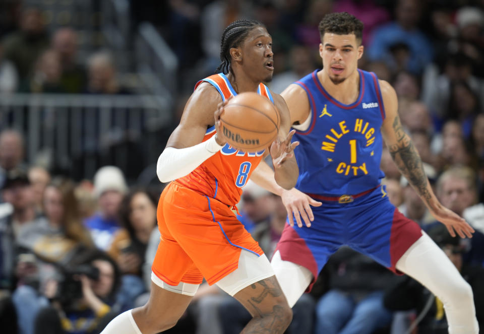 Oklahoma City Thunder forward Jalen Williams, left, passes the ball as Denver Nuggets forward Michael Porter Jr., right, defends in the first half of an NBA basketball game Saturday, Dec. 16, 2023, in Denver. (AP Photo/David Zalubowski)