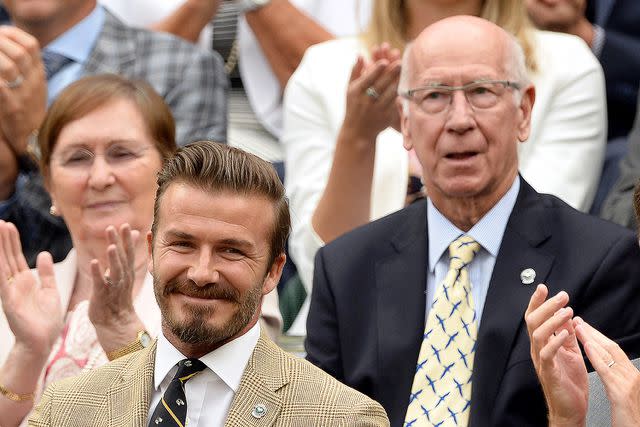 <p>Karwai Tang/WireImage</p> David Beckham and Sir Bobby Charlton seated together at Wimbledon in 2014