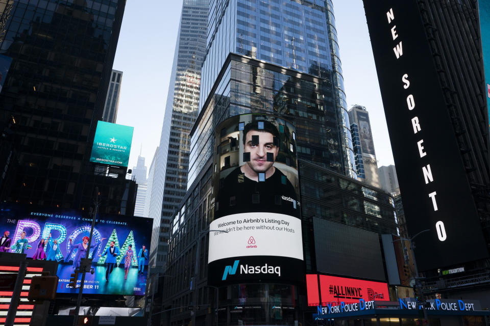 Brian Chesky, CEO of Airbnb, is shown on an electronic screen,, center, at the Nasdaq MarketSite, Thursday, Dec. 10, 2020, in New York. The San Francisco-based online vacation rental company holds its IPO Thursday. (AP Photo/Mark Lennihan)