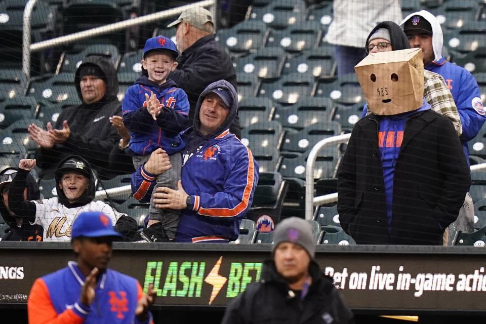 New York Mets fans, one wearing a paper bag over their head, watch as the Mets play the Washington Nationals during the first inning in the first baseball game of a doubleheader, Tuesday, Oct. 4, 2022, in New York. (AP Photo/Frank Franklin II)