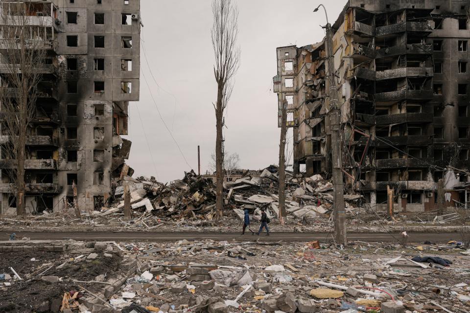 April 5, 2022: People walk by an apartment building destroyed during fighting between Ukrainian and Russian forces in Borodyanka, Ukraine.