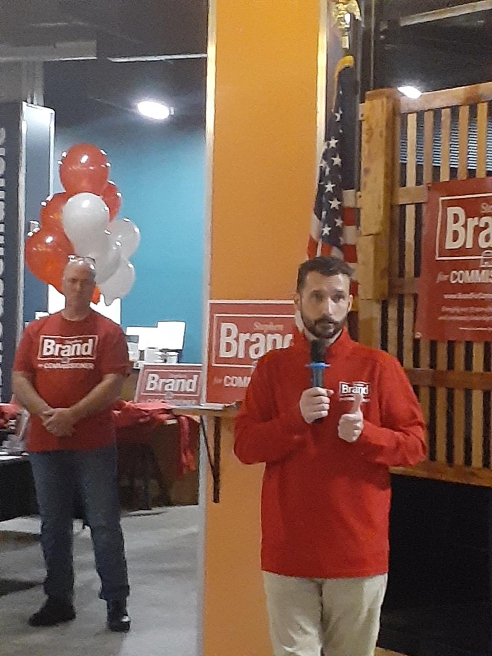 Stephen Brand, Delaware County Commissioner candidate in the the GOP primary election this year, speaks to a crowd of supporters while a supporter, Delaware County Sheriff Tony Skinner, looks on during a downtown campaign kickoff Thursday night. Brand, who is president of the Muncie Sanitary District Board and also chairman of the Greater Muncie Area Chamber of Commerce Board, also addressed some of he questions regarding the seizure of firearms from his home by federal agents last February.