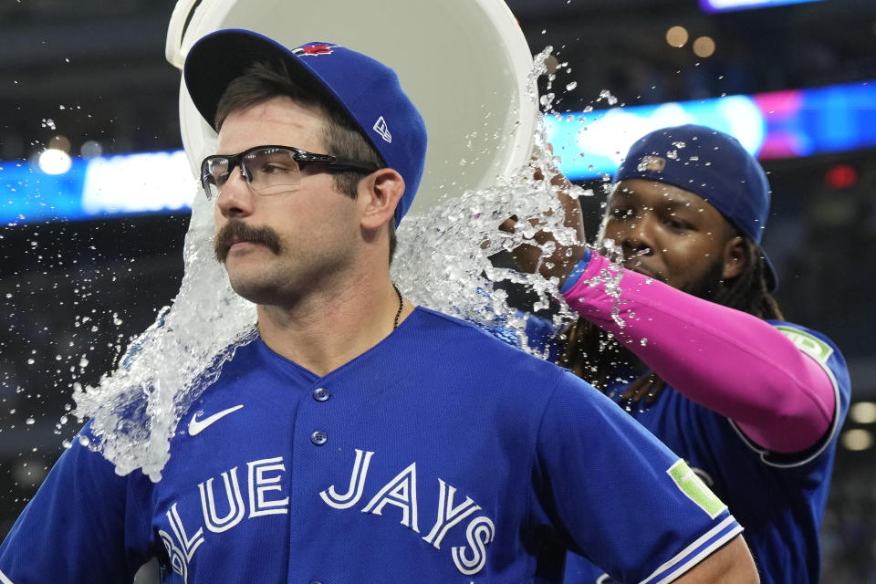 Toronto Blue Jays first baseman Vladimir Guerrero Jr., right, pours ice water over teammate Davis Schneider, left, after they defeated the Cleveland Guardians in a baseball game in Toronto, Saturday, Aug. 26, 2023. (Frank Gunn/The Canadian Press via AP)