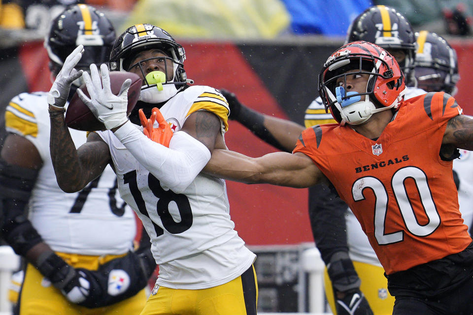 Pittsburgh Steelers wide receiver Diontae Johnson (18) catches a pass with Cincinnati Bengals cornerback DJ Turner II (20) defending for a first down during the first half of an NFL football game in Cincinnati, Sunday, Nov. 26, 2023. (AP Photo/Jeffrey Dean)