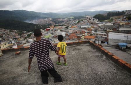 Igor, 6, and his handicapped uncle Claudio, 43, walk on the roof of their house in Brasilandia slum, in Sao Paulo February 10, 2015. REUTERS/Nacho Doce
