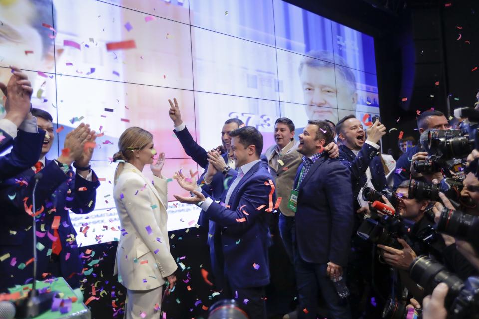 FILE - Ukrainian comedian and presidential candidate Volodymyr Zelenskiy, center, and his wife Olena Zelenska celebrate a victory with their supporters at his headquarters after the second round of presidential elections in Kiev, Ukraine, April 21, 2019. (AP Photo/Sergei Grits, File)