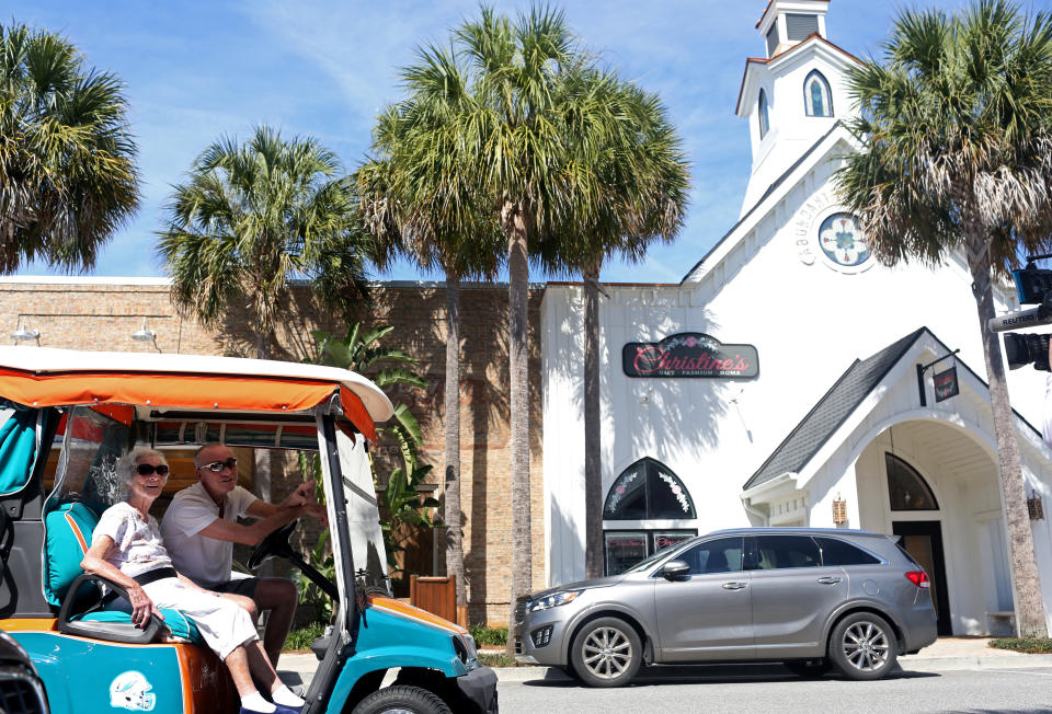 (LR) Mildred Kerrigan, 97 anni, e suo figlio Kevin Kerrigan, 65 anni, in visita da Westchester, NY, guidano un carrello da golf tra le cancellazioni di eventi legati al coronavirus a Brownwood Paddock Square a The Villages, Florida, Stati Uniti, in vista dell'imminente Democratic primario, 15 marzo 2020. REUTERS/Yana Paskova