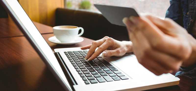 Woman typing numbers from a credit card into a laptop