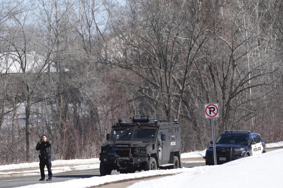 A police officer stands near a police vehicle with what appears to be bullet pockmarks near the scene where two police officers and a first responder were shot and killed Sunday, Feb. 18, 2024, in Burnsville, Minn. (AP Photo/Abbie Parr)