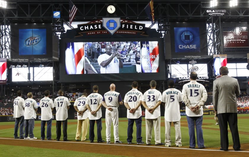 Members of the 2001 Arizona Diamondbacks listen as Jesse McGuire plays the national anthem during reunion ceremonies of the 2001 World Series champions, Saturday, Sept. 10, 2011, in Phoenix, before the Diamondbacks' baseball game against the San Diego Padres. (AP Photo/Rob Schumacher, Pool)