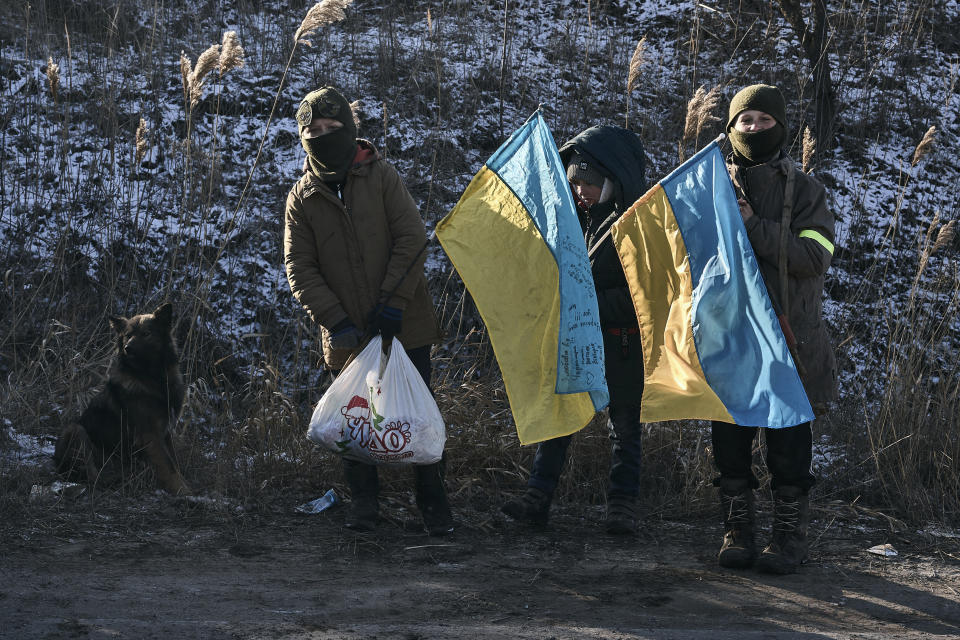 Ukrainian children hold national flags as they stand guard at an improvised checkpoint close to Sloviansk, Donetsk region, Ukraine, Wednesday, Jan. 11, 2023.(AP Photo/Libkos)