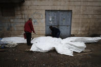 Men try to identify the bodies of earthquake victims recovered outside a hospital, in Aleppo, Syria, Monday, Feb. 6, 2023. A powerful earthquake rocked wide swaths of Turkey and neighboring Syria on Monday, toppling hundreds of buildings and killing and injuring thousands of people. (AP Photo/Omar Sanadiki)