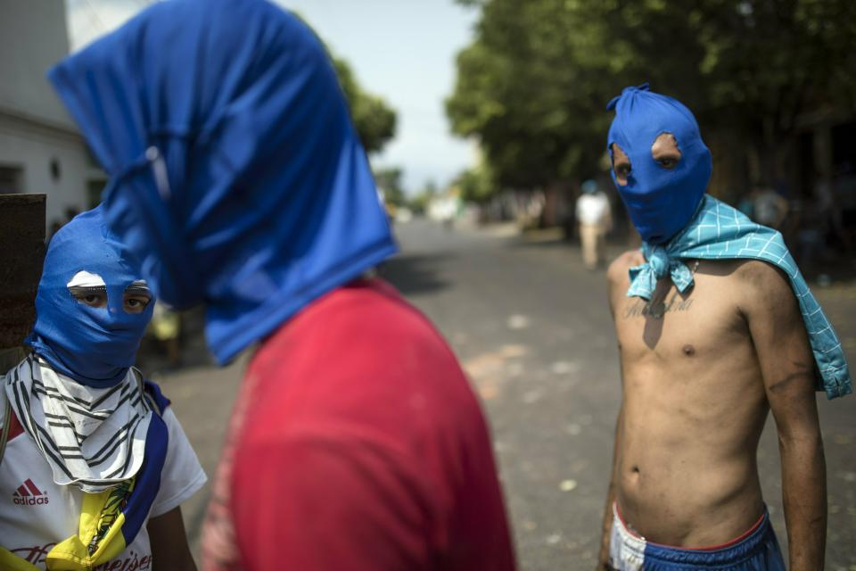 Masked anti-government protesters gather a few blocks from the border bridge in Urena, Venezuela, Sunday, Feb. 24, 2019, on the border with Colombia where Venezuelan soldiers continue to block humanitarian aid from entering. A U.S.-backed drive to deliver foreign aid to Venezuela on Saturday met strong resistance as troops loyal to Venezuelan President Nicolas Maduro blocked the convoys at the border and fired tear gas on protesters. (AP Photo/Rodrigo Abd)