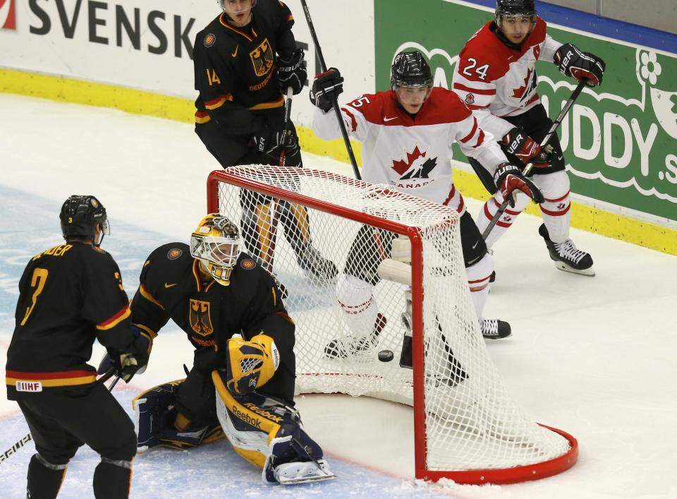 Canada's Anderson scores on Germany's goalie Cupper as Germany's Bender watches the play during the first period of their IIHF World Junior Championship ice hockey game in Malmo