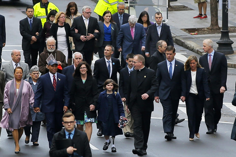 Family members of the victims of the 2013 Boston Marathon bombings are joined by Massachusetts Governor Deval Patrick (baseball cap, L) and Boston Mayor Marty Walsh (3rd R) as they walk to the finish line for a wreath-laying ceremony at the site of the first bomb blast in Boston, Massachusetts April 15, 2014. (REUTERS/Brian Snyder)