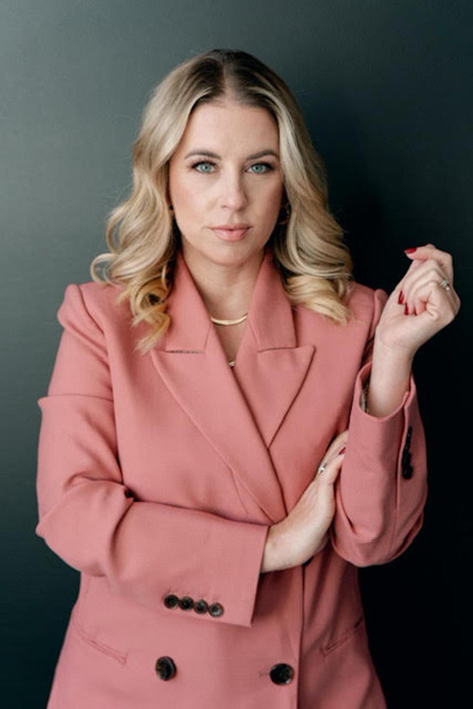 A photo of a woman in a pink blazer.