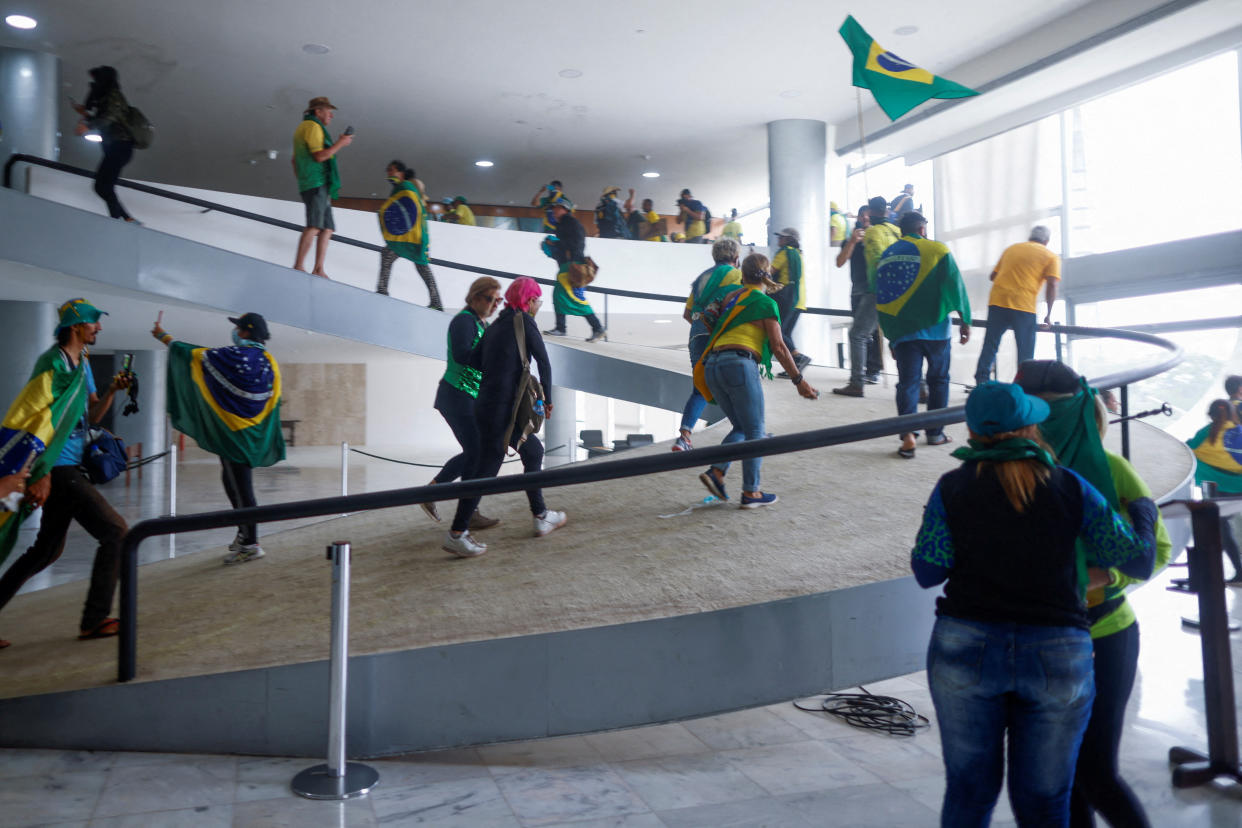 Supporters of Brazil's former President Jair Bolsonaro rush up a ramp in Planalto Palace.