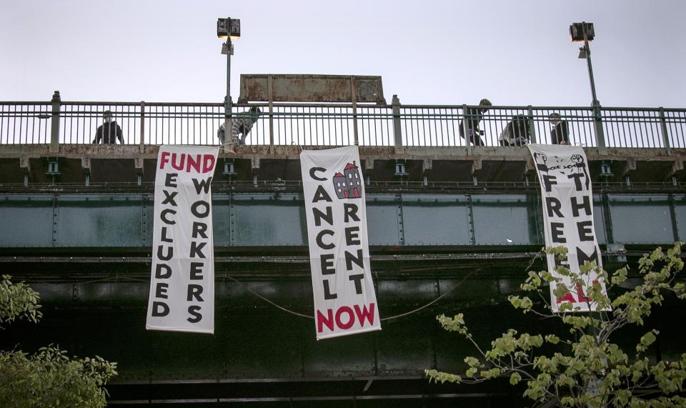 FILE - In this May 21, 2020, file photo, people from a support organization for immigrant and working class communities unfold banners, including one advocating rent cancelation, on a subway platform in the Queens borough of New York during a vigil memorializing people who died from coronavirus. The pandemic has shut housing courts and prompted authorities around the U.S. to initiate policies protecting renters from eviction. But not everyone is covered, and some landlords are turning to threats and harassment to force tenants out. (AP Photo/Bebeto Matthews, File)