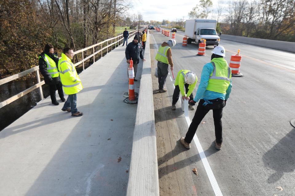 The Franklin County Engineer's Office's efforts to address racial disparities by building pedestrian pathways and better connections to underserved neighborhoods include this wider, handicap accessible sidewalk alongside the Refugee Road bridge over the Big Walnut Creek. From left is engineer's office diversity and inclusion coordinator Simone Burley, bridge engineer Ed Herrick, Franklin County Engineer Cornell Robertson. Applying a stripe to Refugee Road are, from left, Shelly & Sands employees Dalton Wood, Dylan Wood and Keshawn Underwood.